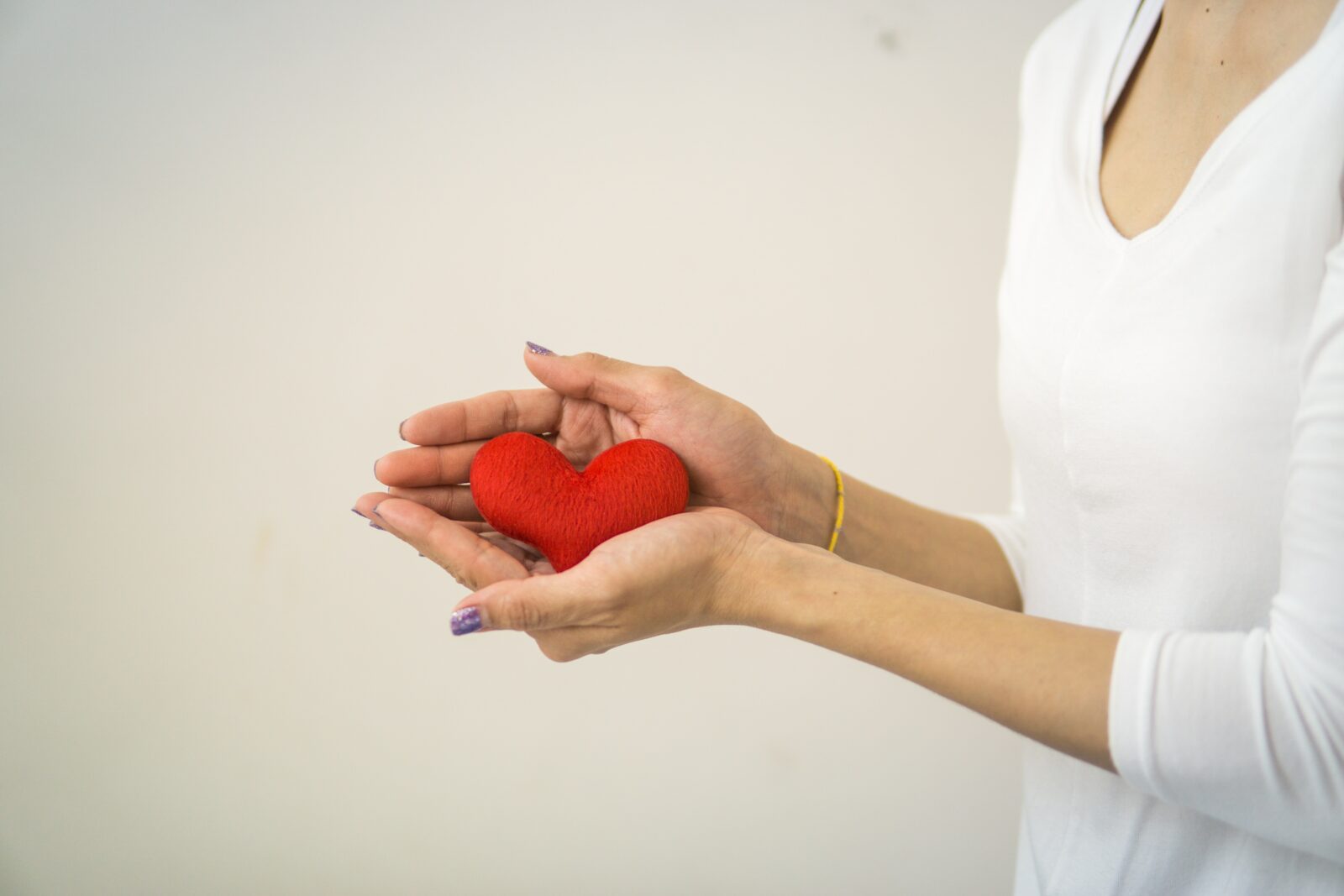 Woman wearing a white shirt and holding a woven heart.
